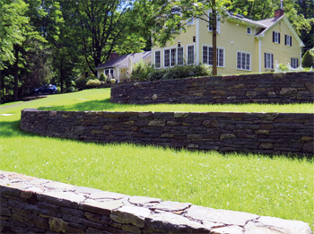 Stone walls and lawns leading up a hill to the home.